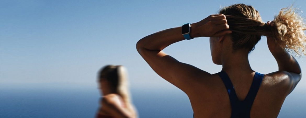 A man is looking at his watch while standing next to another woman.