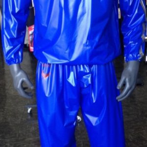 A man in blue rain suit standing next to a wall.