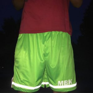 A person wearing shorts with reflective tape on them.