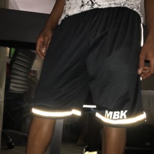 A man wearing black shorts with white reflective tape.