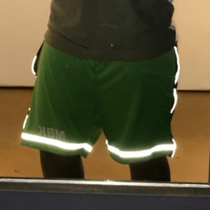 A person wearing green shorts and reflective tape.