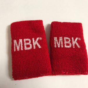 A pair of red wrist bands with the letters mbk on them.