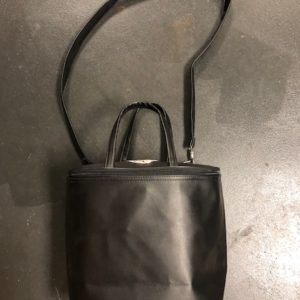 A black purse is sitting on the ground.