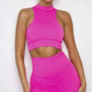 A woman in pink outfit standing next to wall.